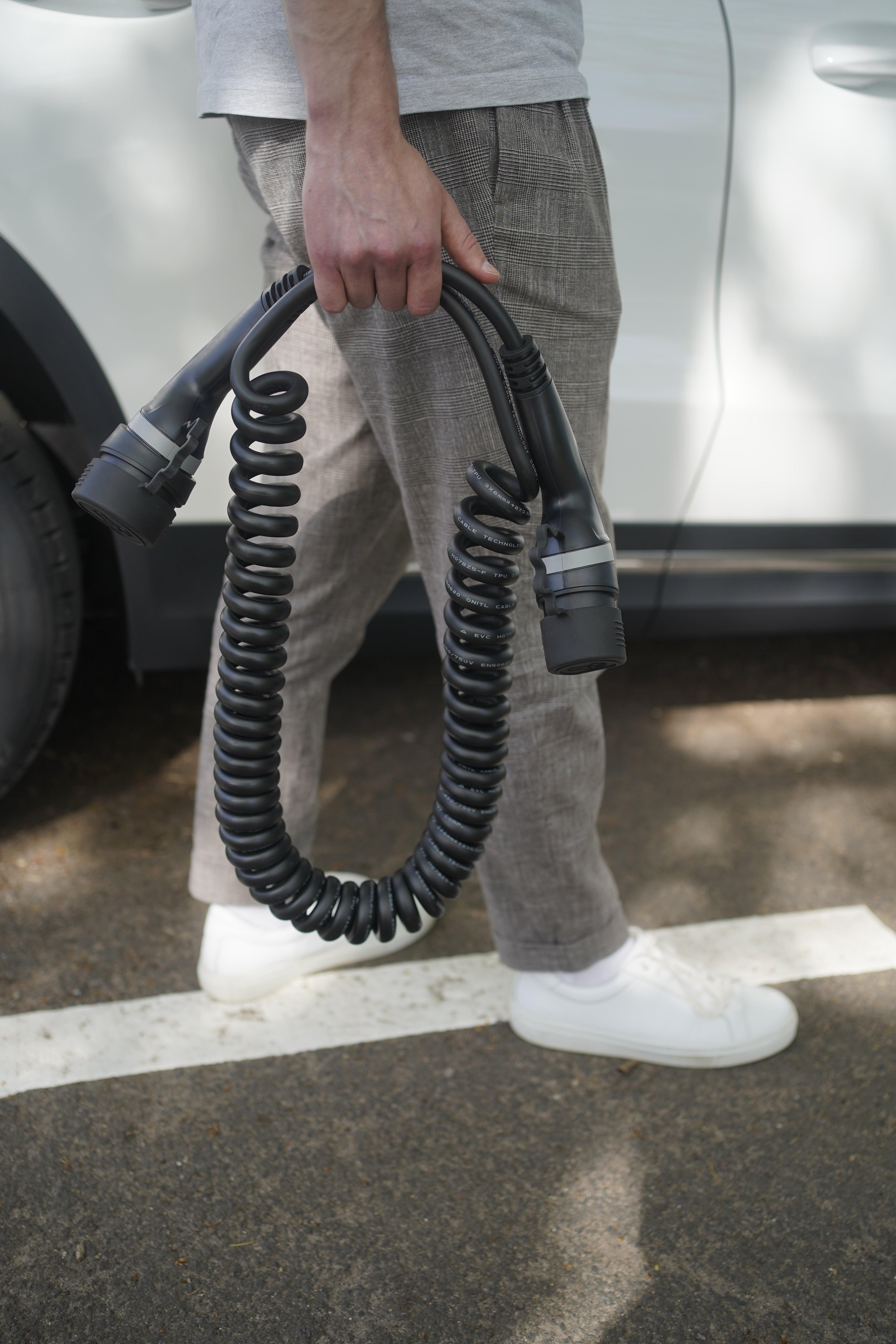 Mann trägt Ecopoint Typ 2 Ladekabel 22kW mit spiraler Form in Grau
